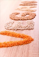 Word Vegan made of lentils, buckwheat, beans, rice and chickpeas on a wooden background