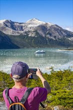 Man photographing the cruise ship Stella Australis in Pia Bay in front of the Pia Glacier, Alberto