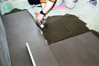 Tiler lays modern large floor tiles in a bathroom