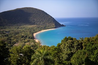 View from a mountain onto an empty sandy beach, the turquoise-coloured sea and the surrounding