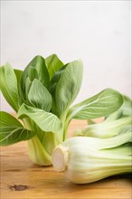Fresh green bok choy or pac choi chinese cabbage on a brown wooden background. Side view, close up,