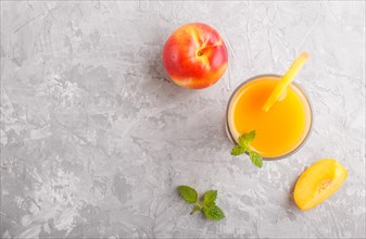 Glass of peach juice on a gray concrete background. Morninig, spring, healthy drink concept. Top