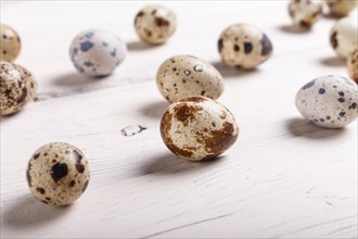 Raw quail eggs on a white wooden background