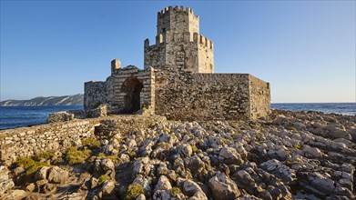 Old ruined fortress with tower-like structure against a clear blue sky next to the sea, octagonal