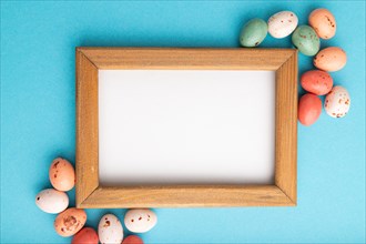Composition with candies and wooden frame on blue pastel background. copy space, top view, flat