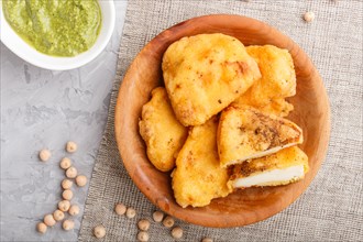 Traditional indian food paneer pakora in wooden plate with mint chutney on a gray concrete
