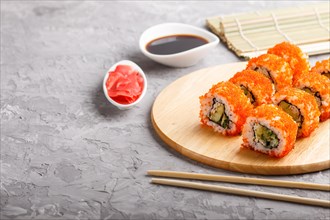 Japanese maki sushi rolls with flying fish roe, chopsticks, soy sauce and marinated ginger on