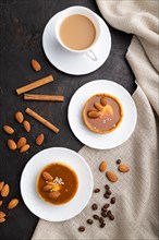 Sweet tartlets with almonds and caramel cream with cup of coffee on a black concrete background and