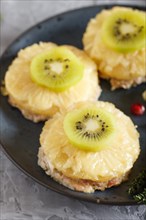 Pieces of baked pork with pineapple, cheese and kiwi on gray background, top view, close up,