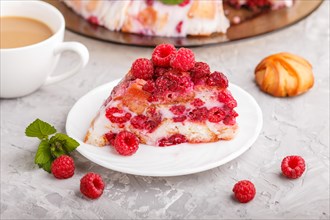 Homemade jelly cake with milk, cookies and raspberry on a gray concrete background with cup of
