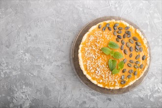 Traditional american sweet pumpkin pie decorated with mint, sesame and pumpkin seeds on a gray