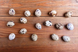 Raw quail eggs on a brown wooden background. top view
