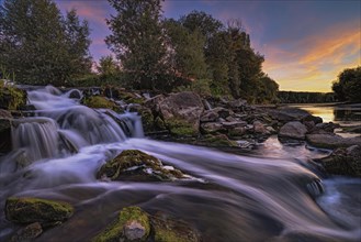 A waterfall in the evening light on the Old Rhine near Speyer as a long exposure