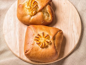 Sweet buns on a wooden board and linen tablecloth