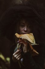 A mysterious blurred image of a woman holding a mushroom with a deep autumnal backdrop