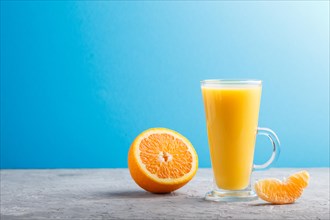 Glass of orange juice on a gray and blue background. Morninig, spring, healthy drink concept. Side
