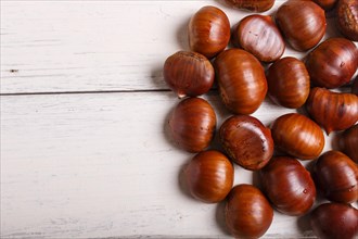 Pile of sweet chestnuts on white wooden background with copy space, top view