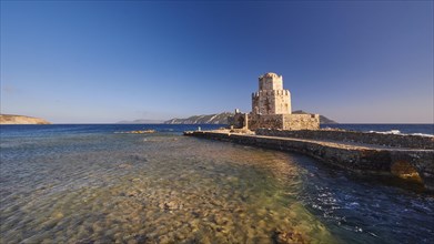 An old castle at sunset overlooking the calm sea, octagonal medieval tower. Bourtzi islet, Methoni