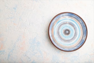Empty blue ceramic plate on white concrete background. Top view, copy space, flat lay