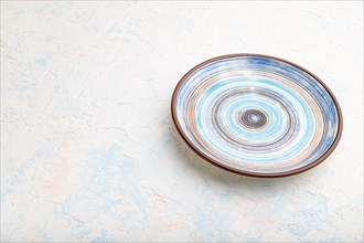 Empty blue ceramic plate on white concrete background. Side view, copy space