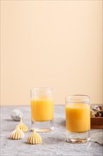 Sweet egg liqueur in glass with quail eggs and meringues on a gray and orange background. Side