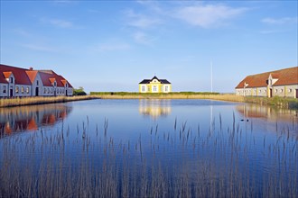 Large houses and the teahouse at Valdemars Slot are reflected in the calm water, Valdemars Slot,