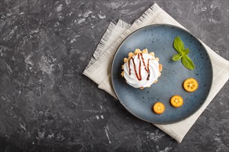 Cake with whipped egg cream on a blue ceramic plate with kumquat slices and mint leaves on a black