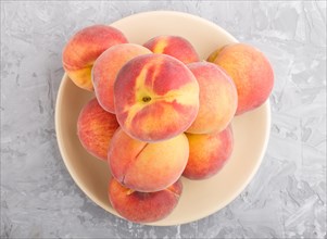 Fresh peaches on a plate on gray concrete background. top view, flat lay, close up