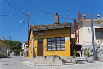 Small house with orange-painted facade and wooden windows on a quiet street, Soufli, Eastern