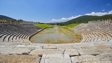 Empty ancient stadium with rows of seats in front of a hilly landscape, archaeological site,
