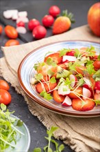Vegetarian fruits and vegetables salad of strawberry, kiwi, tomatoes, microgreen sprouts on black