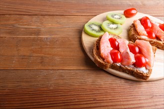 Smoked salmon sandwiches with butter on wooden background. cherry tomatoes. top view, copy space