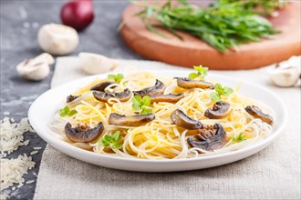 Rice noodles with champignons mushrooms, egg sauce and oregano on white ceramic plate on a black