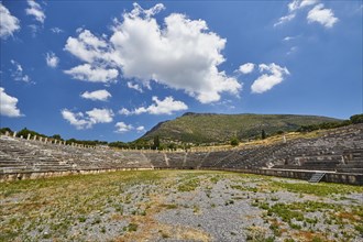 Ancient stadium with many rows of seats, surrounded by grass and sky, Archaeological site, Ancient