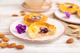 Small cheesecakes with jam and almonds with cup of coffee on a white wooden background and linen