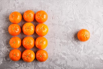 Rows of tangerines forming a rectangle and one tangerine on a gray concrete background, top view,