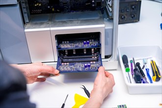 Close-up of the hands of a technician repairing a component of a computer desk in a workshop