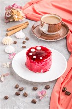Red cake with souffle cream with cup of coffee on a gray concrete background and red textile. side