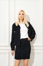 Confident woman in black wool mini skirt and jacket paired with white blouse