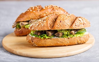 Sprats sandwiches with lettuce and cream cheese on wooden board on a gray concrete background. side
