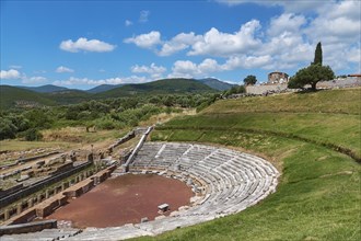 Ancient amphitheatre with rows of seats on a green meadow surrounded by hills, Ancient theatre,