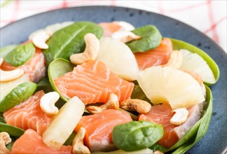 Fresh salmon with pineapple, spinach and cashew on a gray concrete background. Side view, close up,