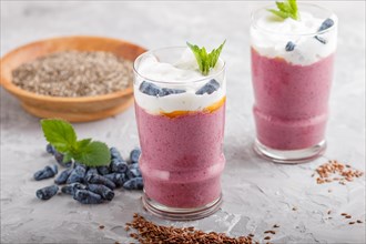 Smoothie with honeysuckle, linen and chia in a glass on gray concrete background. side view, close