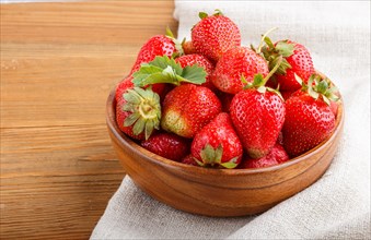Fresh red strawberry in wooden bowl on wooden background. side view, close up