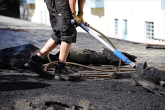 Roofers remove old bitumen and roof waterproofing