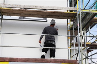 Painter and plasterer working on the facade of a new residential building (Mutterstadt development