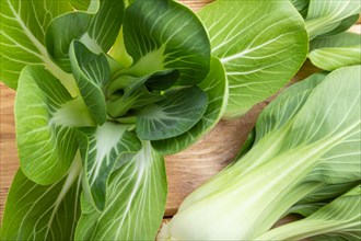 Fresh green bok choy or pac choi chinese cabbage on a brown wooden background. Top view, close up,