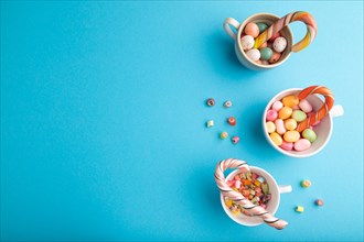 Heap of multicolored caramel candies in cups on blue pastel background. copy space, top view, flat