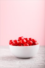 Fresh red sweet cherry in white bowl on gray and pink background. side view, close up, selective