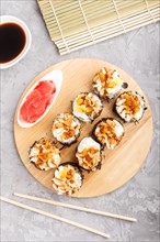 Japanese maki sushi rolls with cream cheese, chopsticks, soy sauce and marinated ginger on wooden